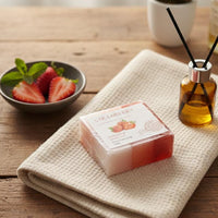 Bar of soap on a towel with a bowl of strawberries and a diffuser in the background