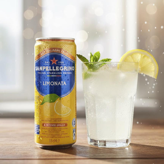 Sanpellegrino Limonata can with a glass of lemonade on a wooden surface.