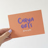 Hand holding an orange card with 'Chrya Gifts' text on a white background
