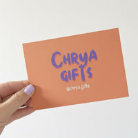 Hand holding an orange card with 'Chrya Gifts' text on a white background