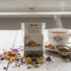 Tea package labeled 'Sea of Blossoms' with a steaming cup of tea on a wooden surface.